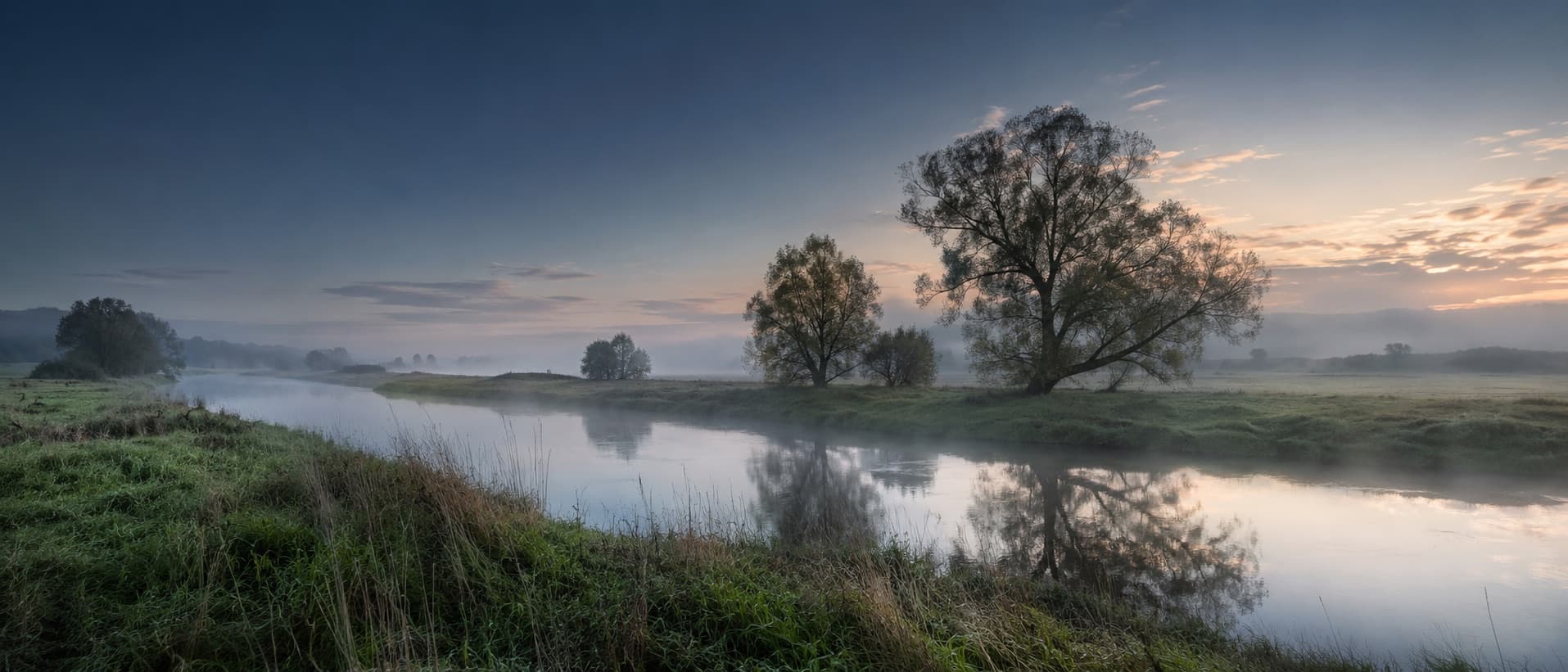Stiller Fluss mit Bäumen im Morgennebel