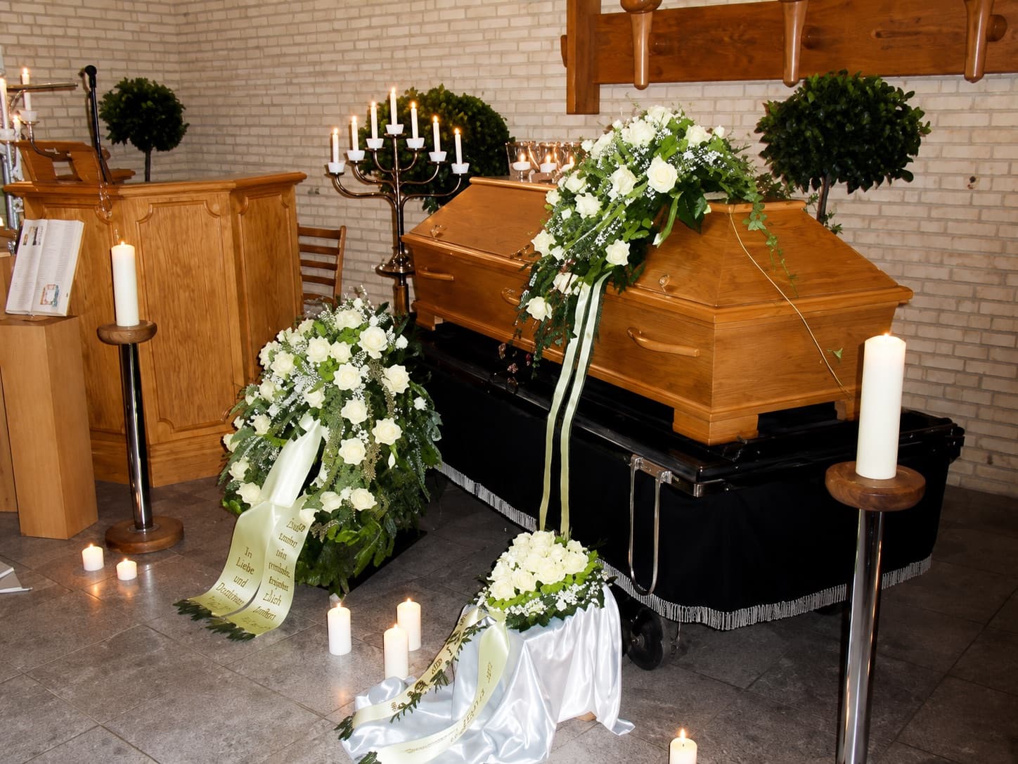Eichensarg mit weißem Blumenschmuck und Kerzen