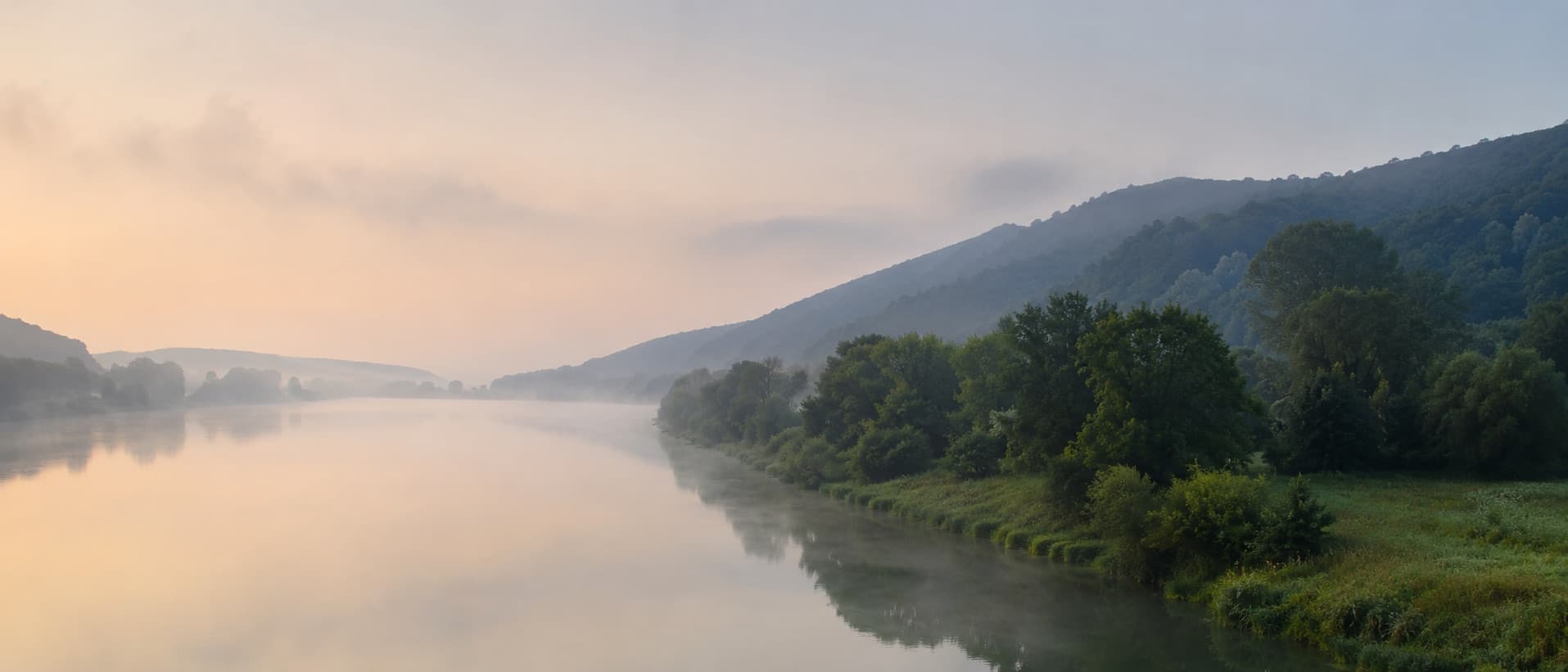 Ruhige Wasseroberfläche am Horizont im Morgenlicht