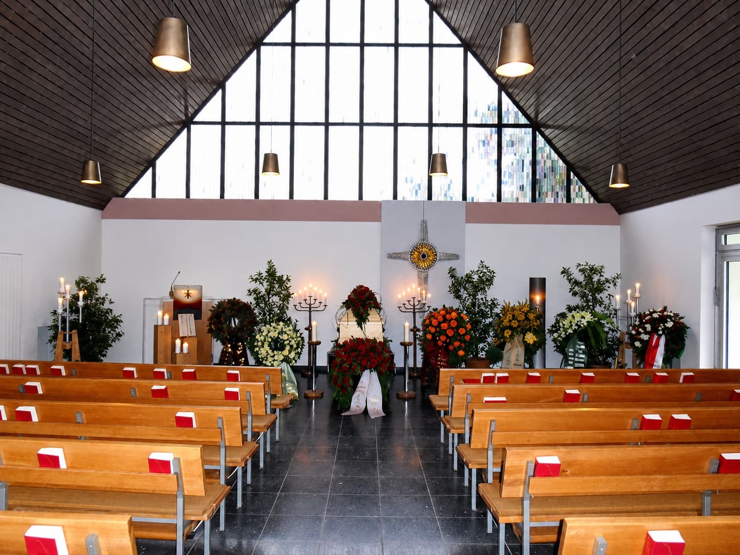 Lichtdurchflutete Trauerhalle mit Blumenschmuck und Kerzen