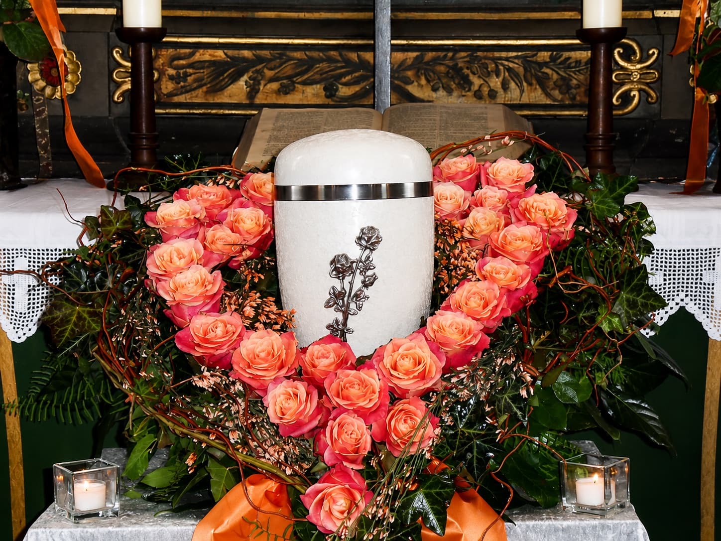 Weiße Urne umgeben von einem Herz aus zartrosa Rosen